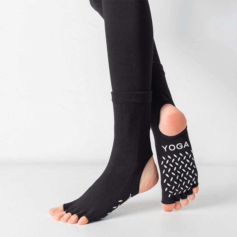 Black silicone non-slip toeless pilates socks with five toes separated, featuring grip design, worn on a foot during yoga.